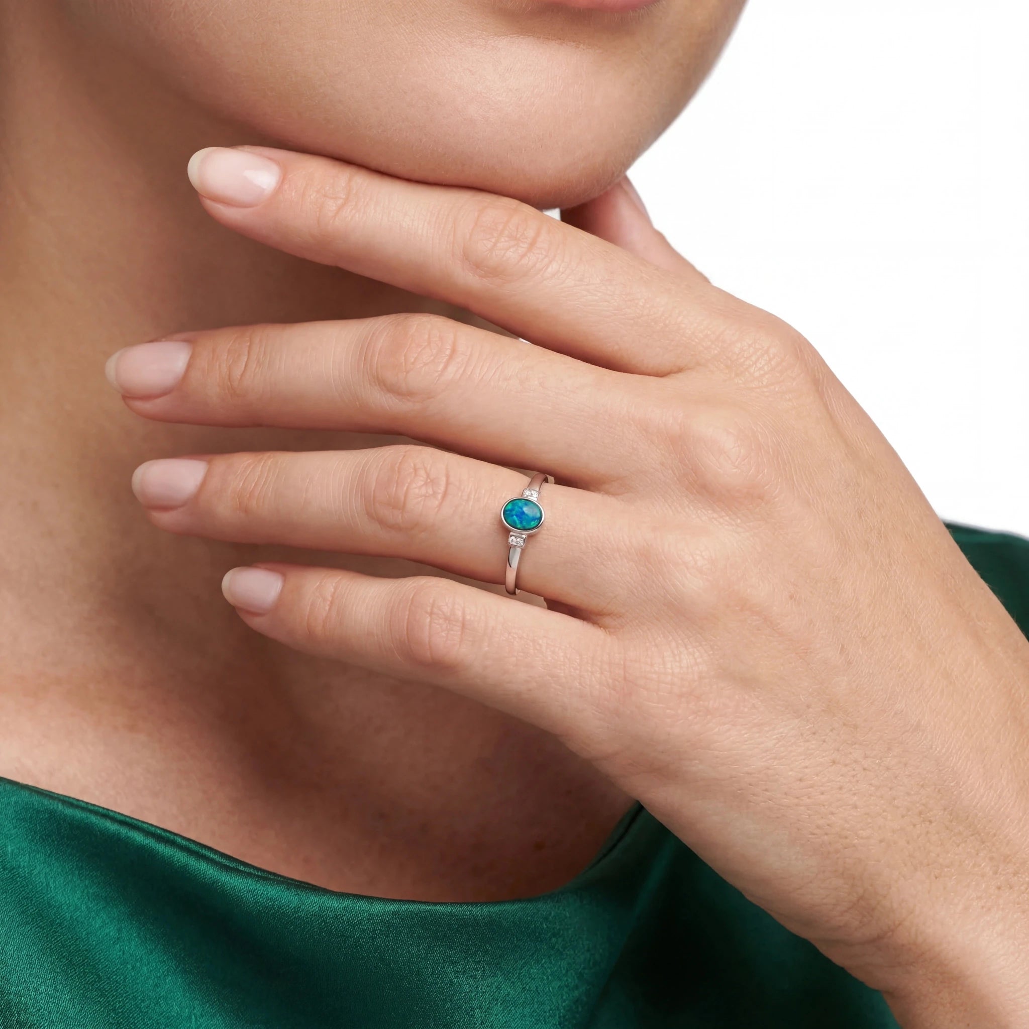 Close-up of a hand wearing a turquoise opal gemstone ring on a neutral background