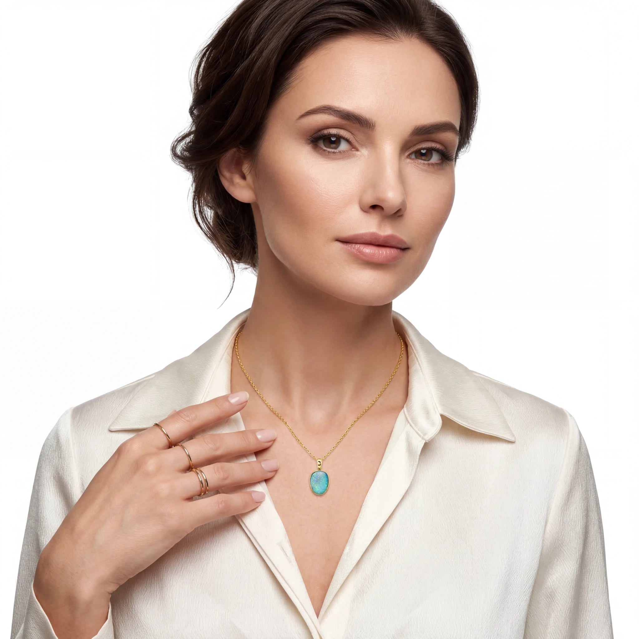 Woman wearing a gold necklace with a turquoise pendant on a white background