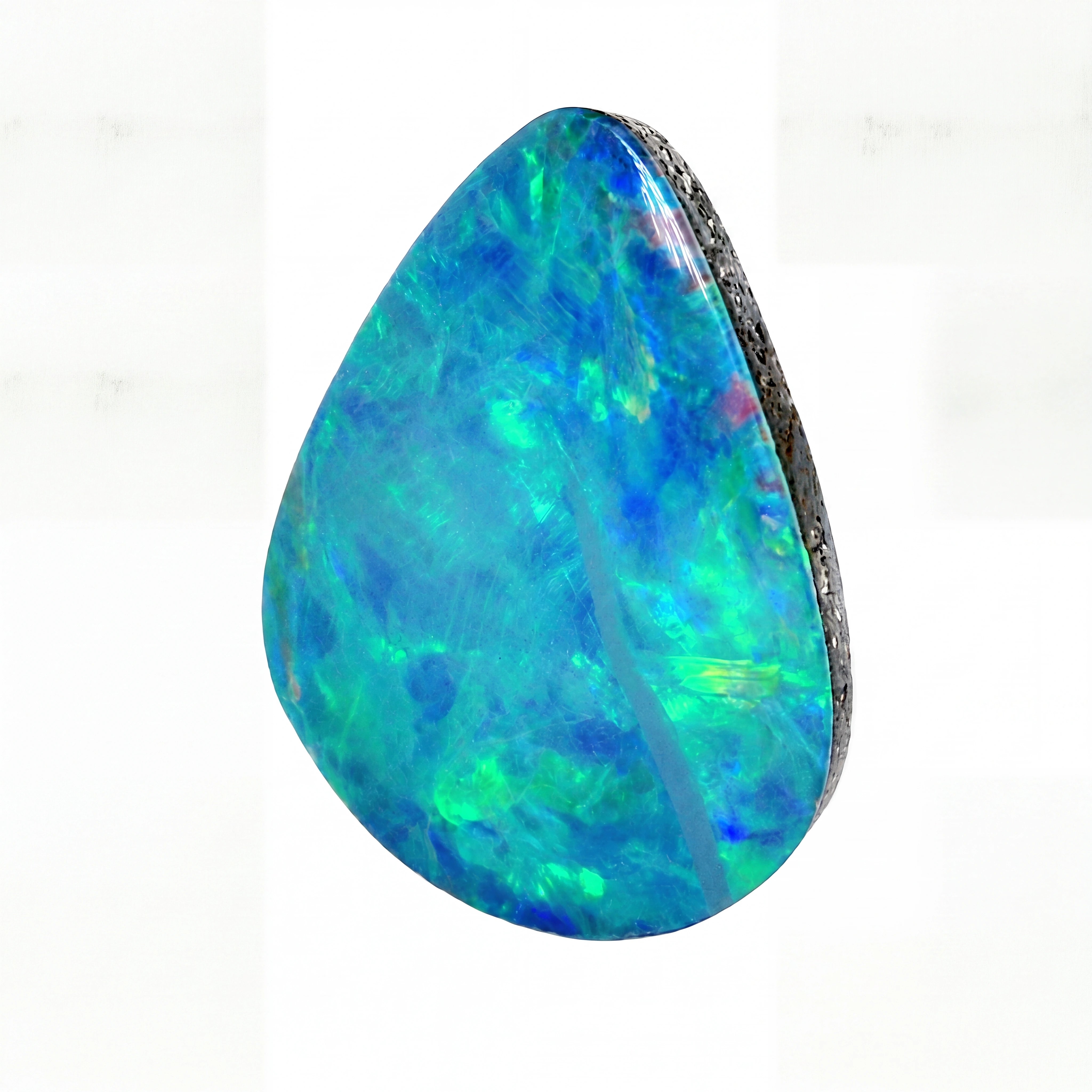A teardrop-shaped loose opal gemstone with vibrant blue, green, and turquoise iridescent play-of-colour, set in a dark rough metallic bezel, shown on a plain white background.