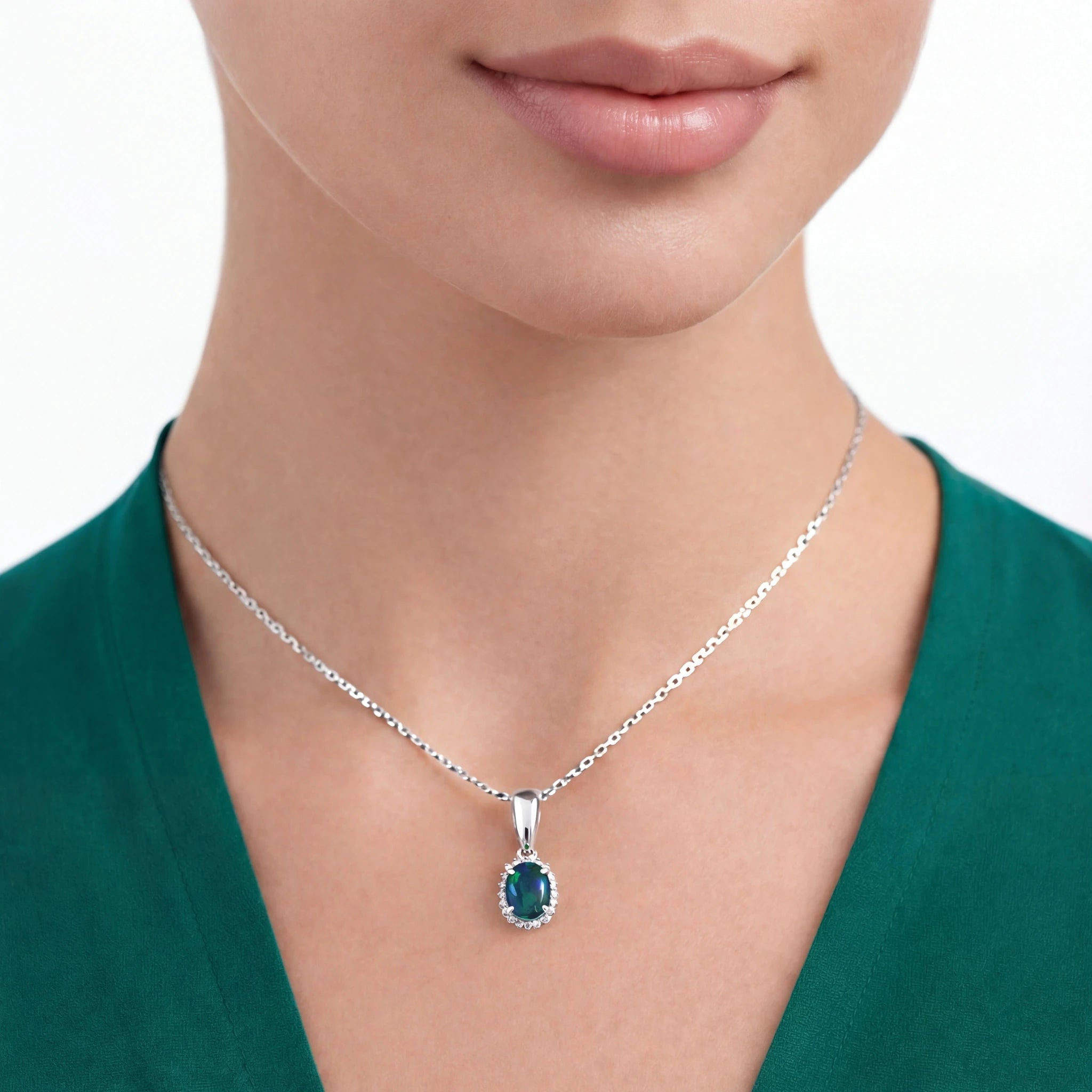 Woman wearing a silver necklace with a green pendant on a white background