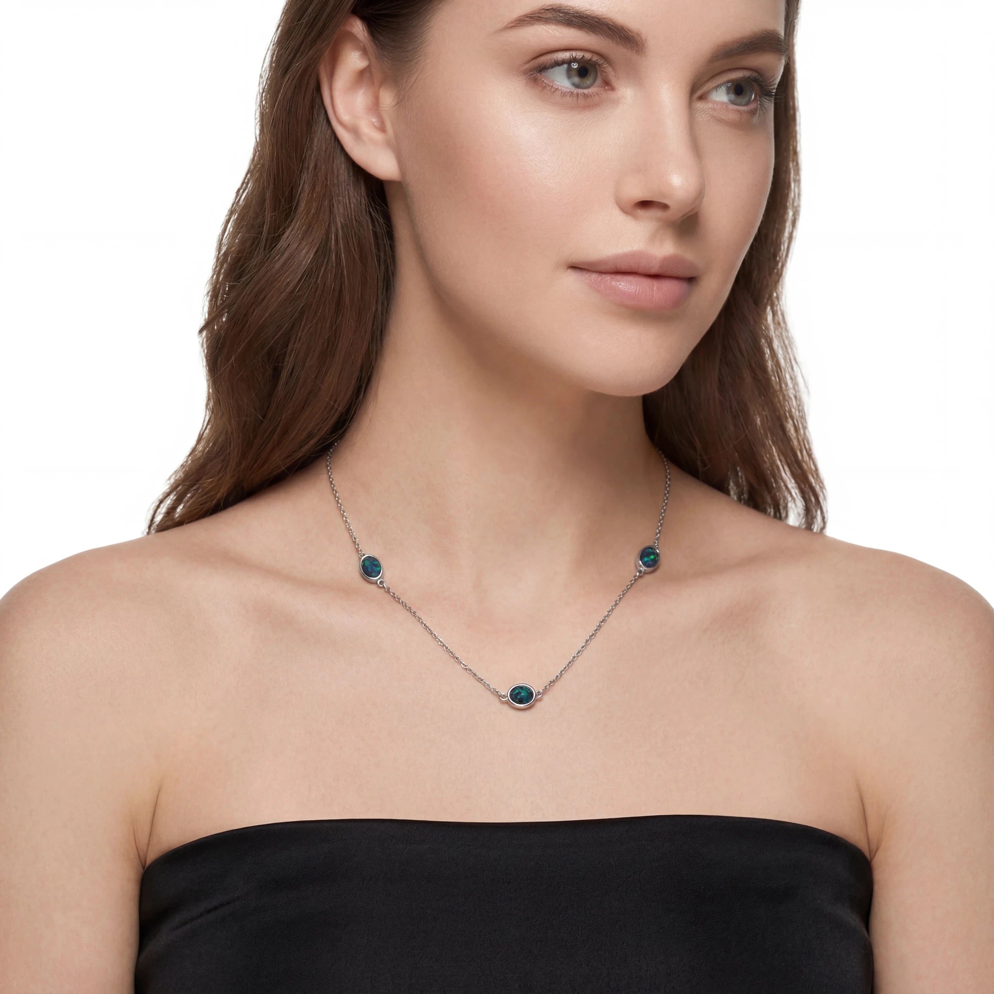 Woman wearing a necklace with green gemstones on a white background