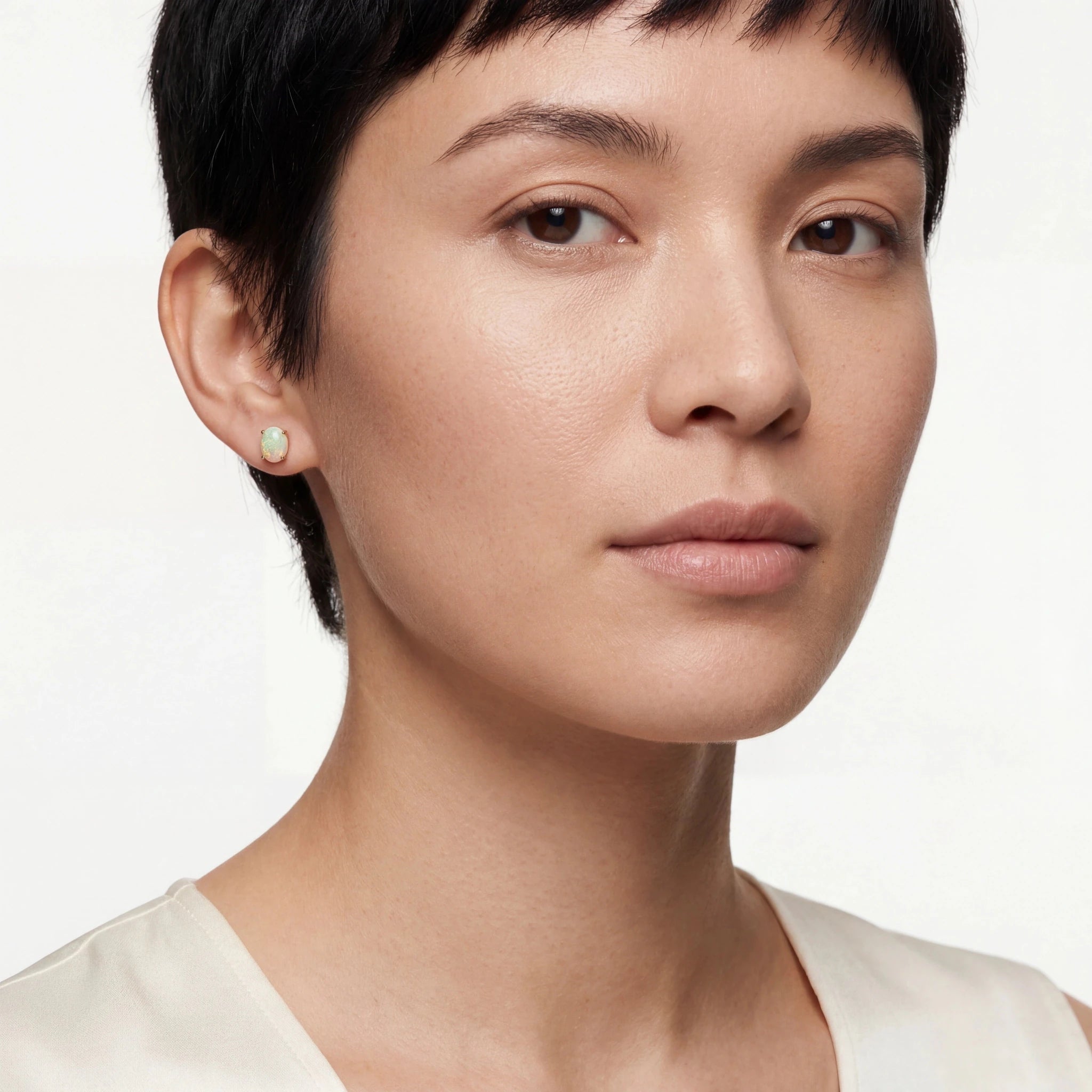 Close-up of a woman wearing a gold opal earring on a white background