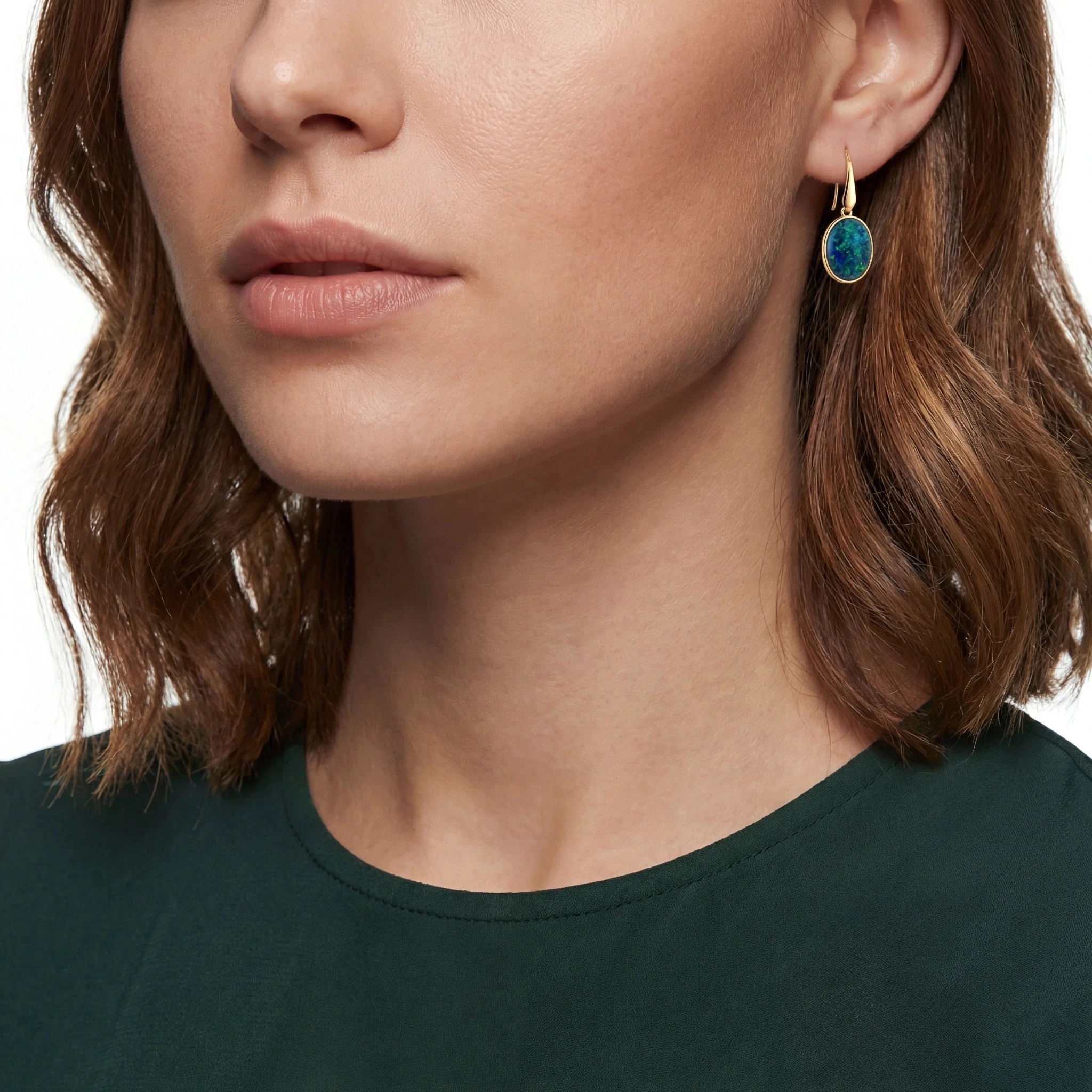 Close-up of a person wearing a green earring with a white background