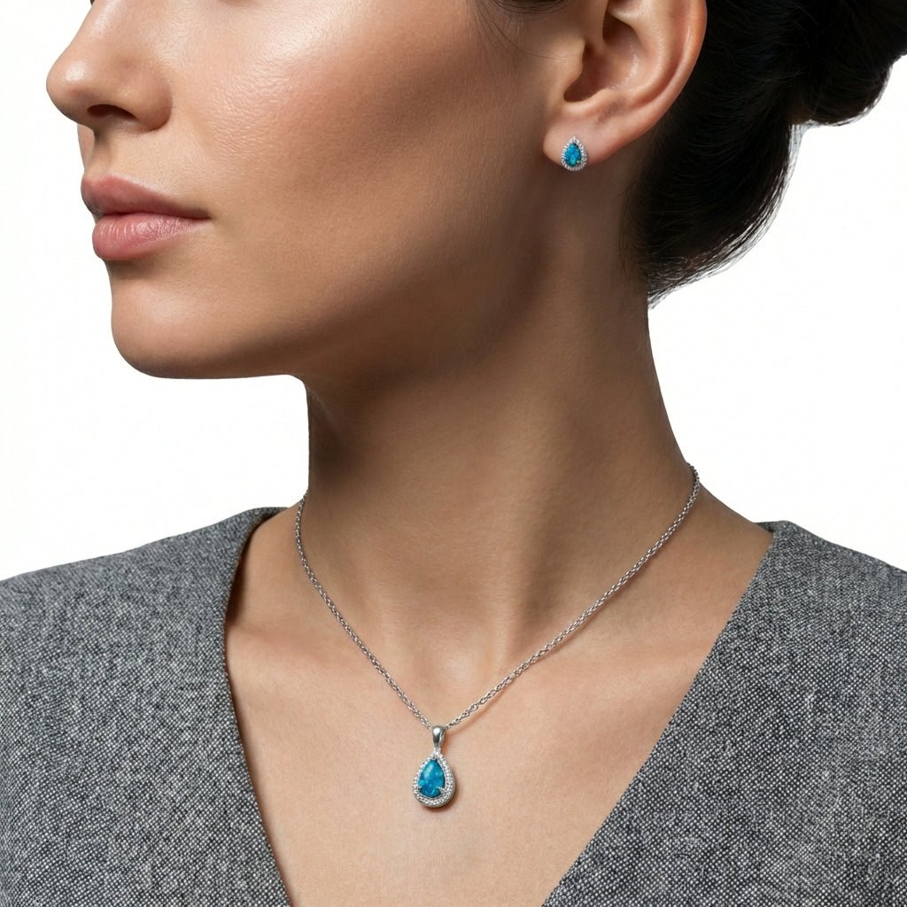 Close-up of a woman wearing a silver necklace with a blue pendant and matching earrings.