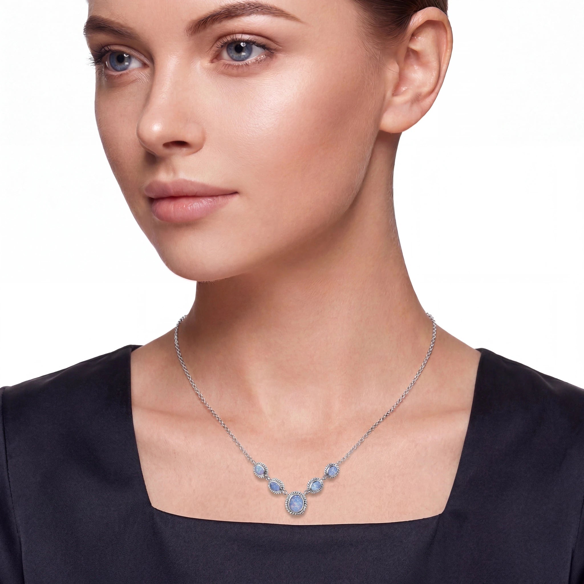 Woman wearing a necklace with blue gemstones on a plain background