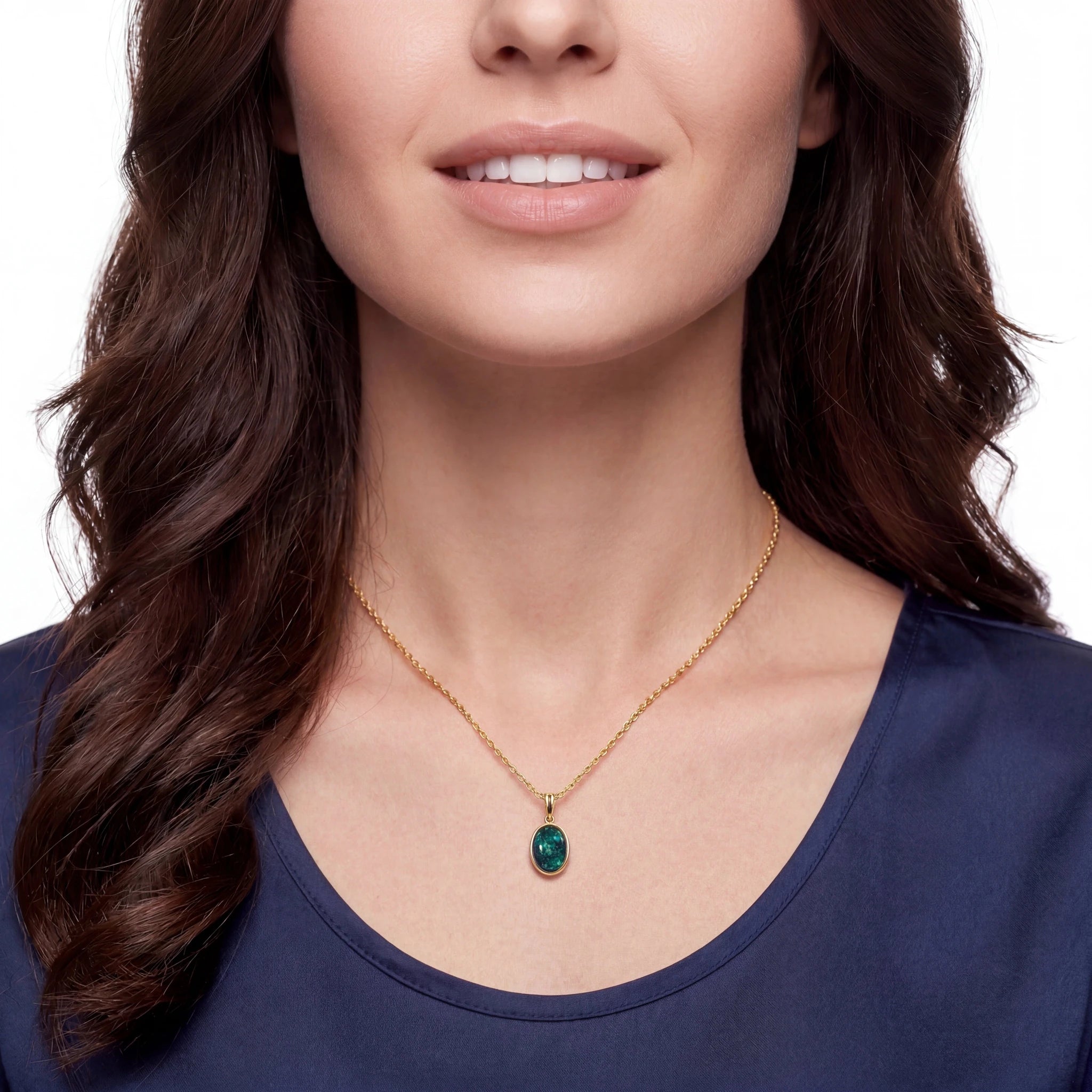 Woman wearing a gold necklace with a green pendant on a white background