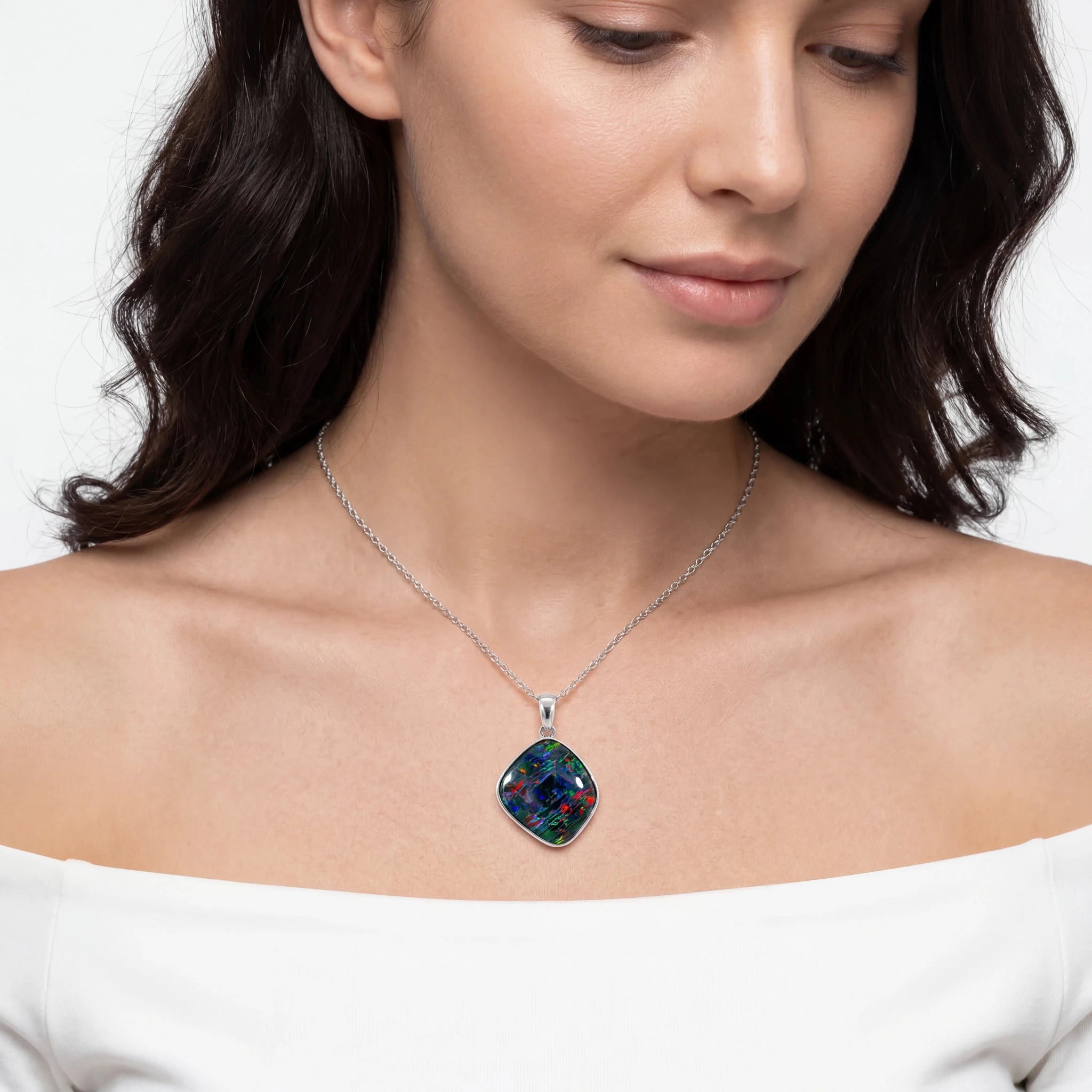 Woman wearing a necklace with a colourful pendant on a plain background