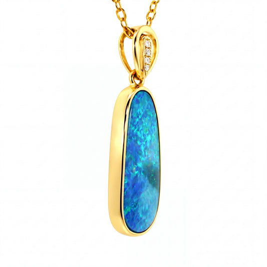 A gold pendant necklace featuring a vertical oval-cut blue opal stone in a polished gold bezel setting, suspended from a gold chain with a small row of clear stones on the bail.