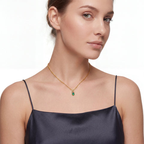 Woman wearing a gold necklace with a green pendant on a white background