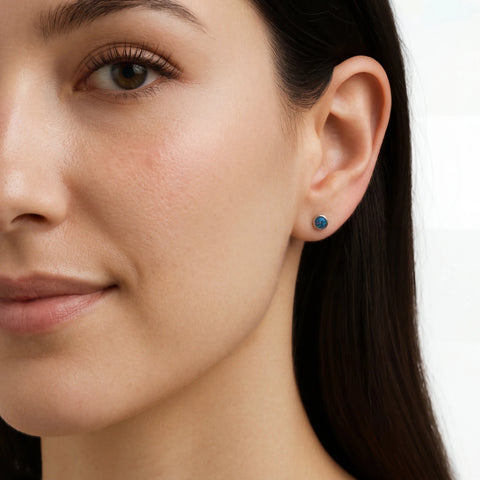 Close-up of a woman wearing a blue opal earring on a white background