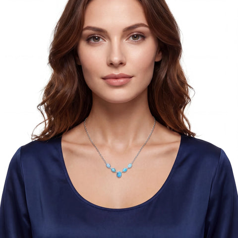 Woman wearing a blue top and necklace with turquoise beads on a white background