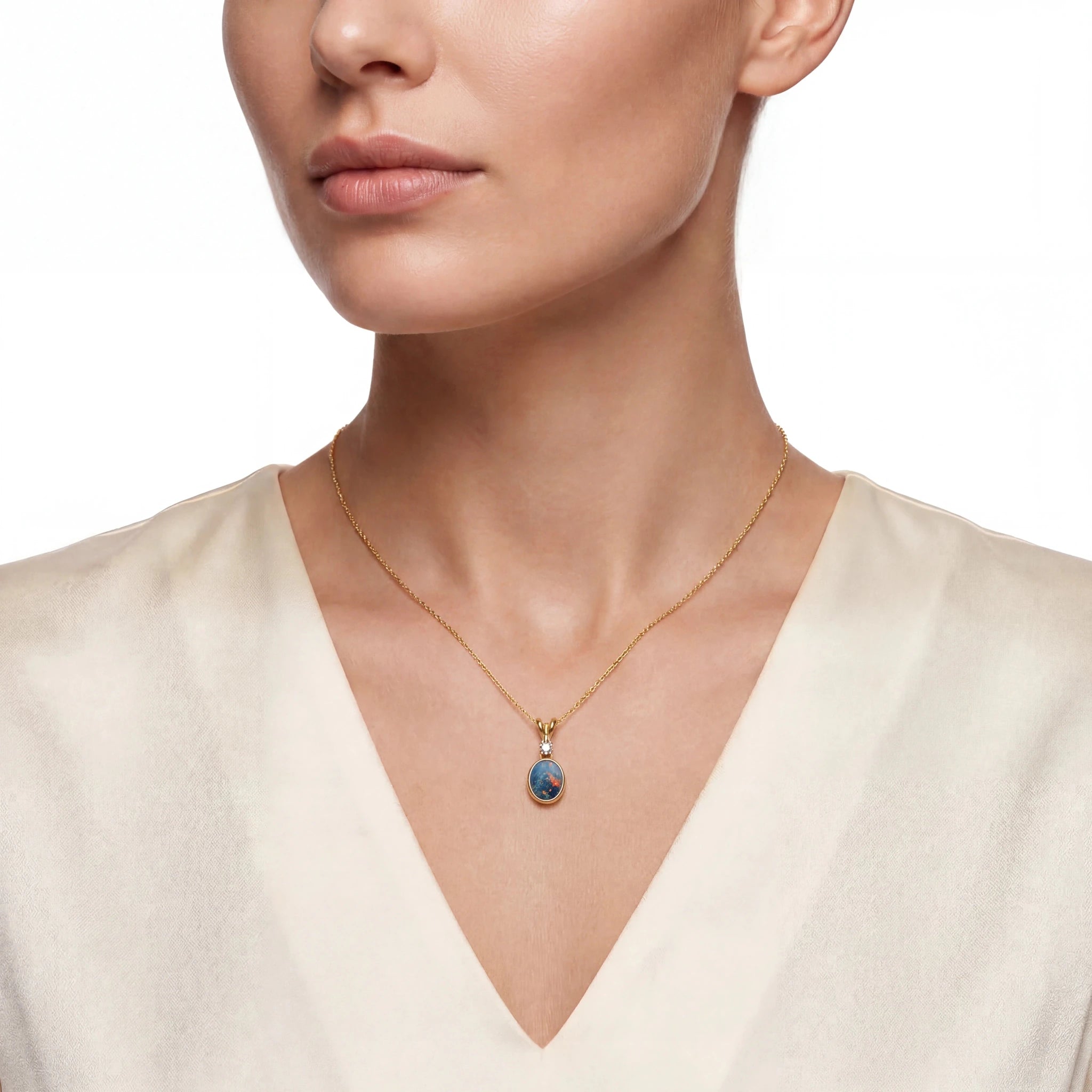 Woman wearing a gold necklace with a blue opal pendant on a white background