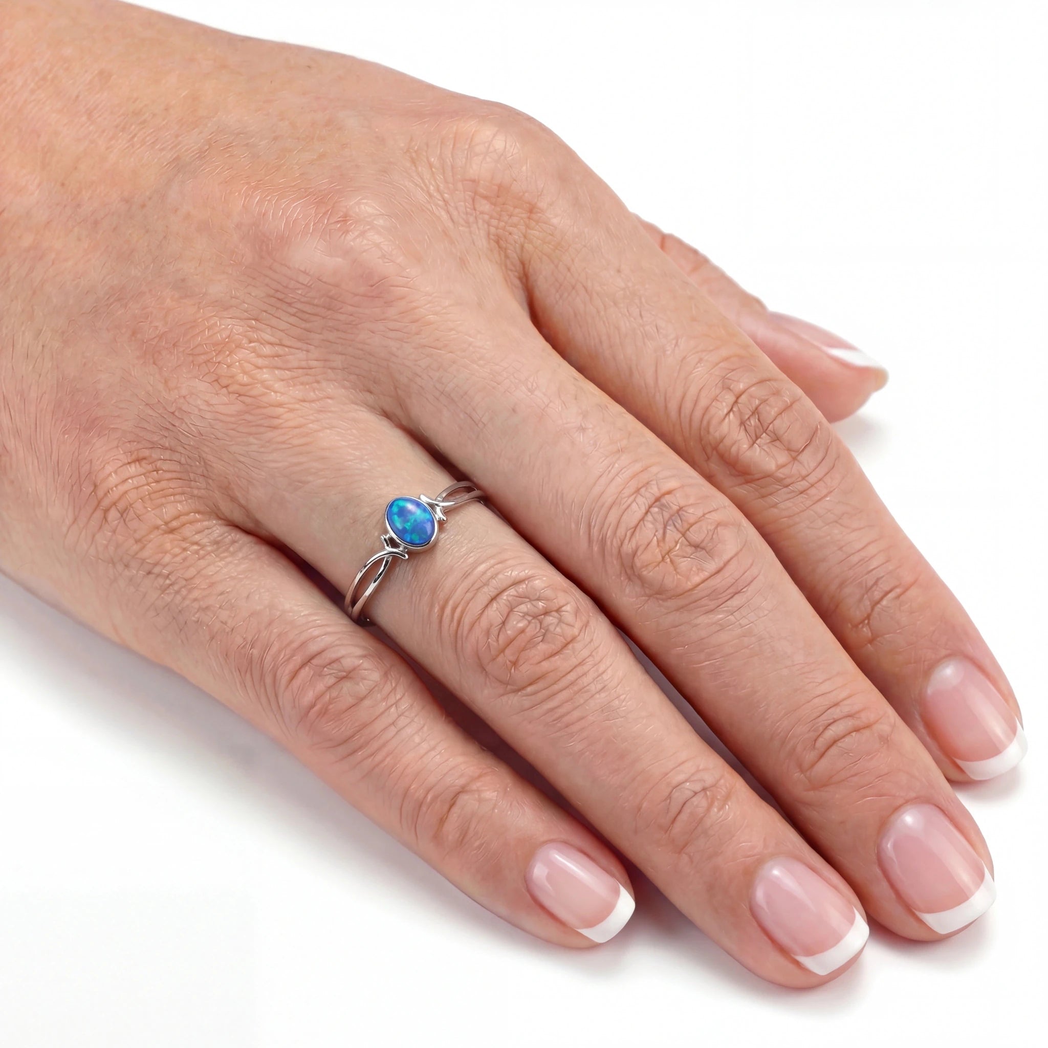 Hand wearing a ring with a blue gemstone on a white background