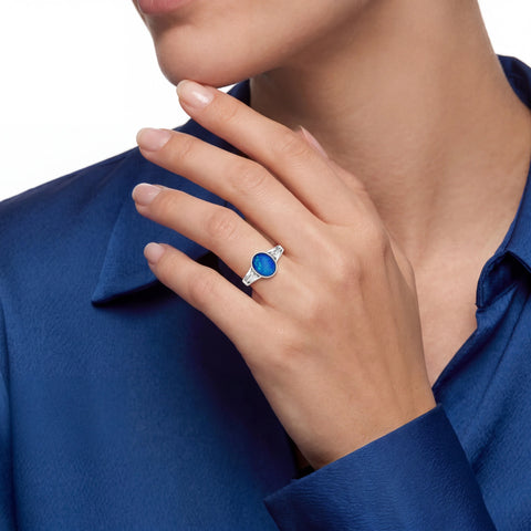 Close-up of a hand wearing a blue gemstone ring on a blue shirt background