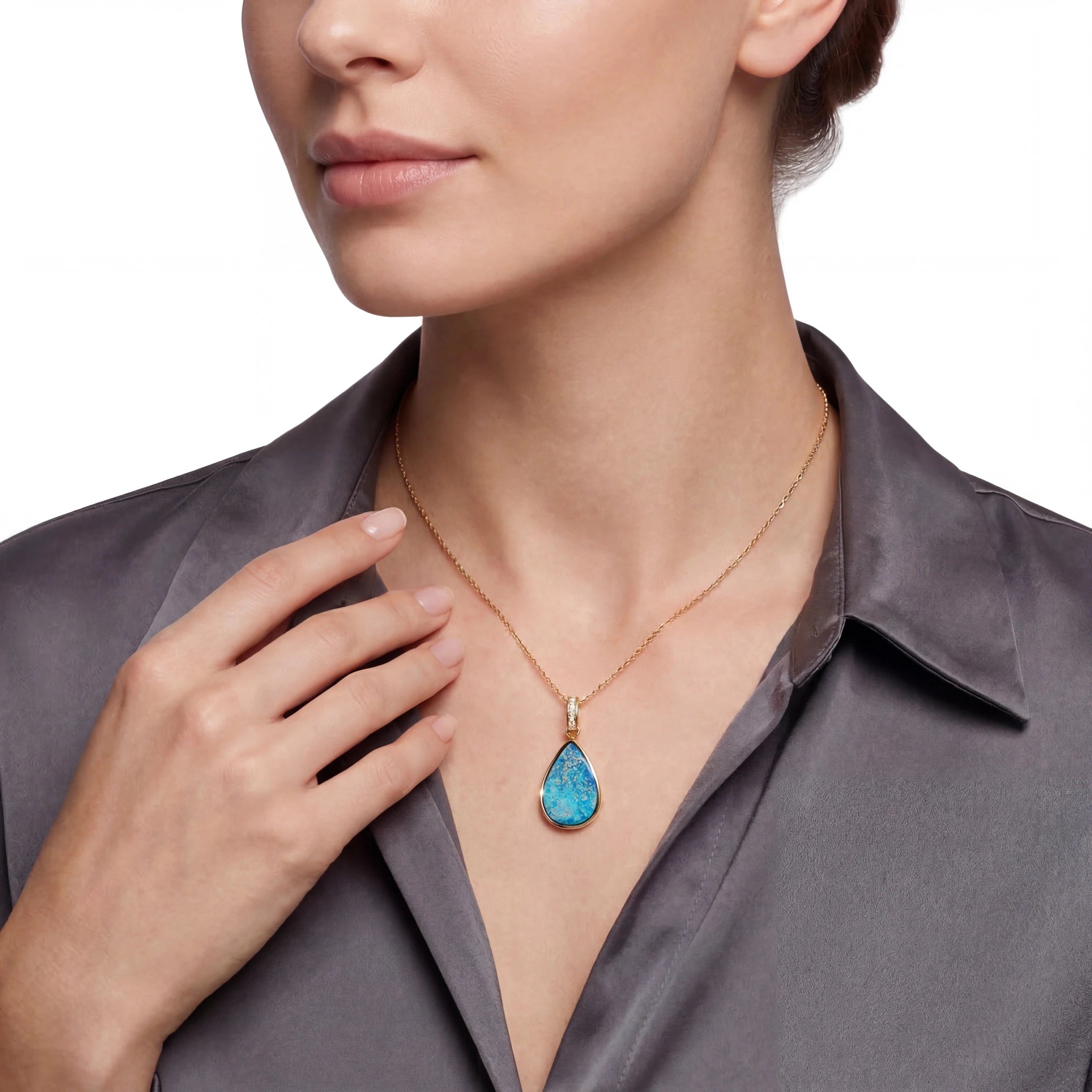Woman wearing a gold necklace with a blue teardrop opal pendant on a white background