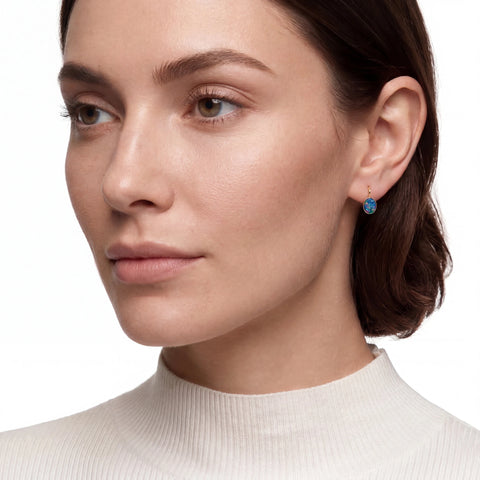 Close-up of a woman wearing a white turtleneck and blue earrings on a white background