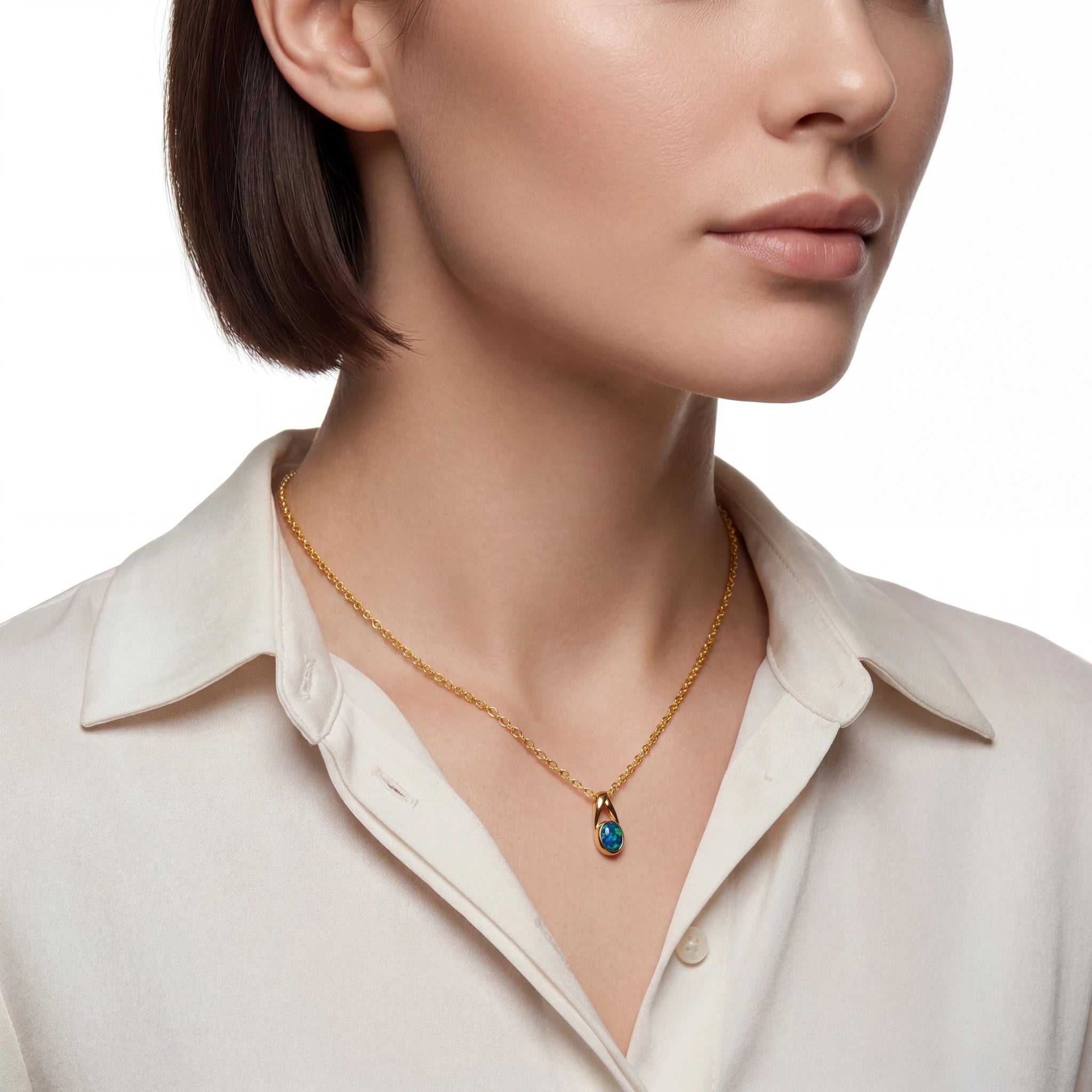 Woman wearing a gold necklace with a blue pendant on a white background