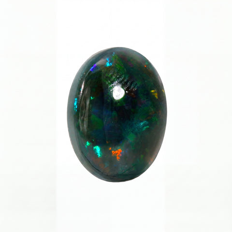 A polished oval cabochon gemstone, likely an opal, displaying a dark black base with vibrant, shifting flashes of green, blue, and orange, set against a plain white background.