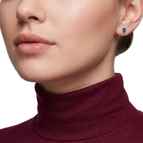 Close-up of a person wearing a burgundy turtleneck sweater and opal earrings