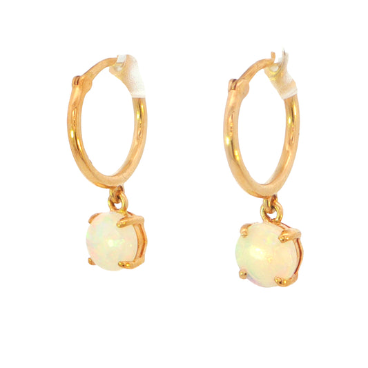 A pair of gold huggie hoop earrings with dangling round white opal gemstones in a four-prong setting, shown on a plain white background.