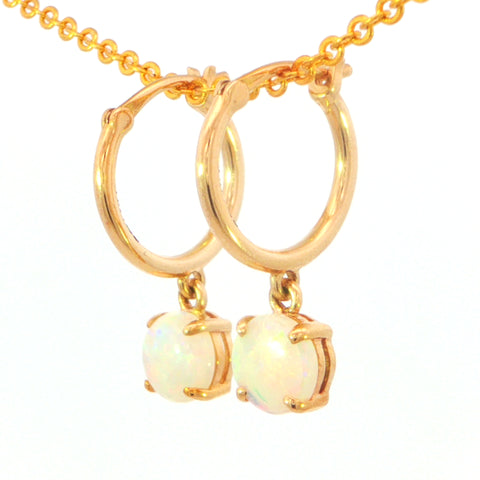 Gold hoop earrings with dangling round iridescent opal-like stones, shown on a gold chain against a white background.