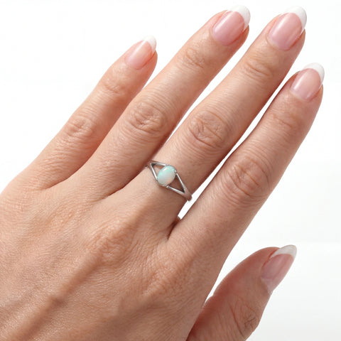 Hand wearing a silver ring with a gemstone on a white background