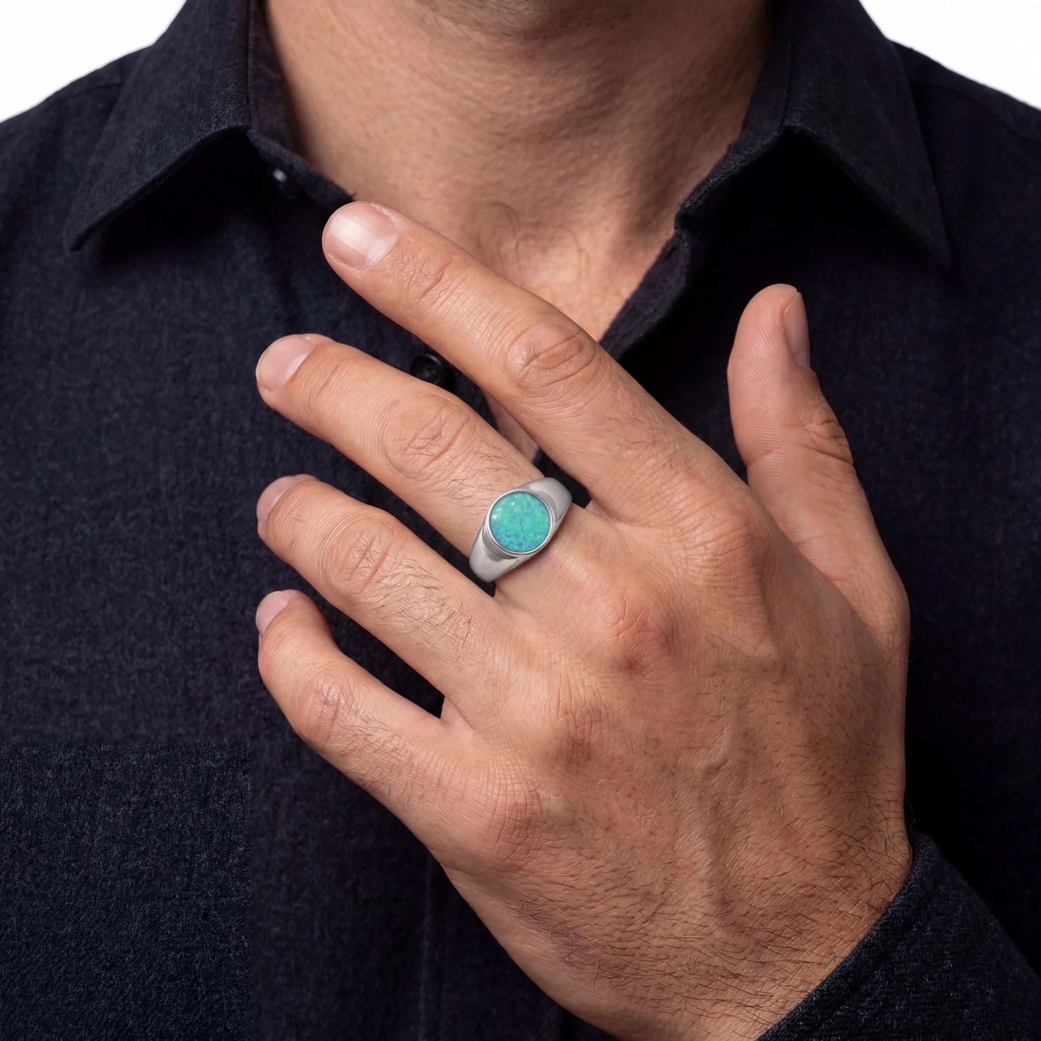 Hand wearing a turquoise opal stone ring on a dark shirt background