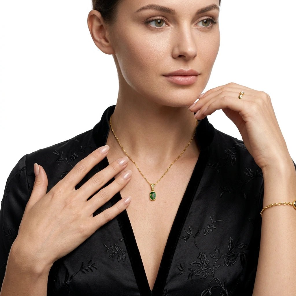 Woman wearing a gold necklace with a green pendant on a white background