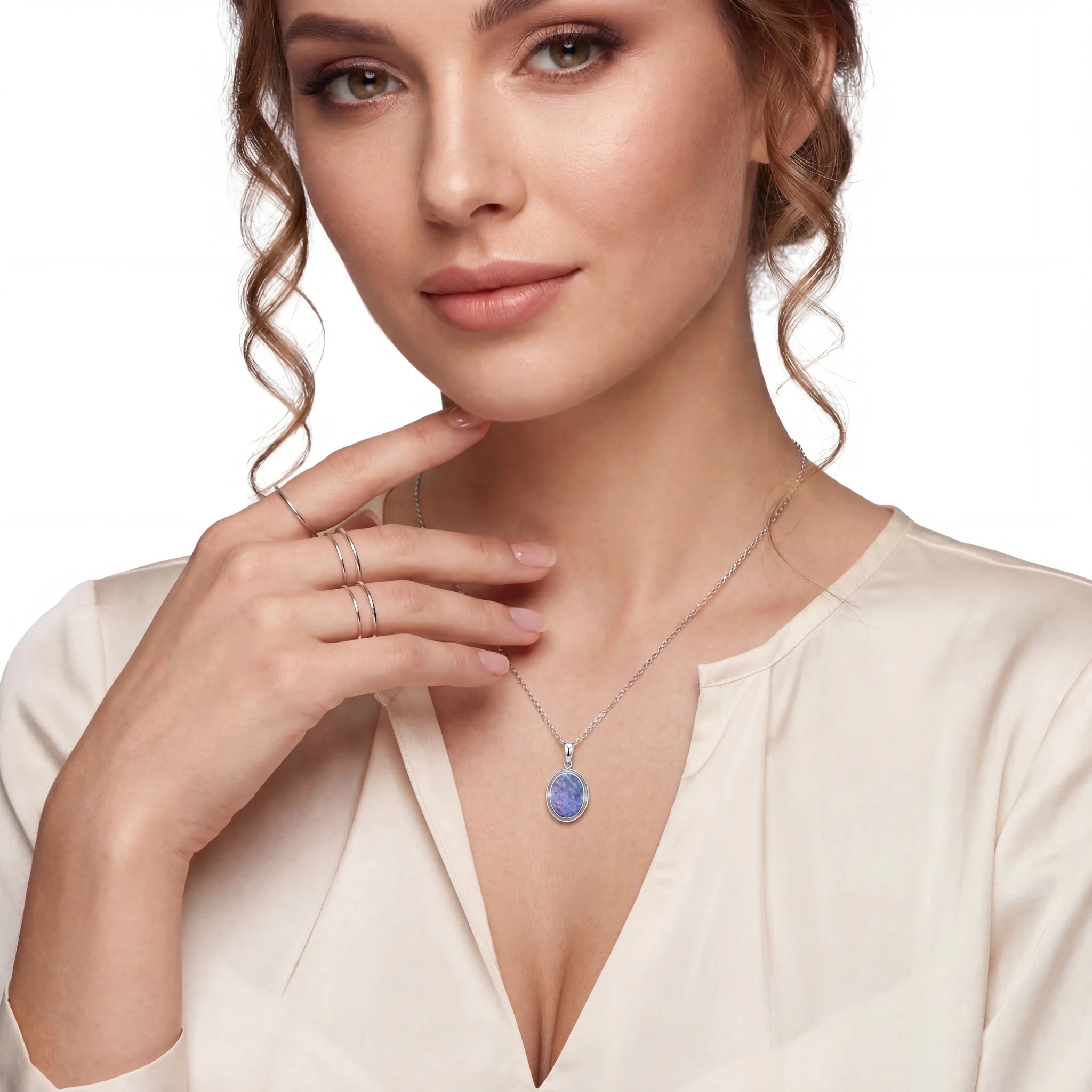 Woman wearing a necklace with a blue pendant on a plain background