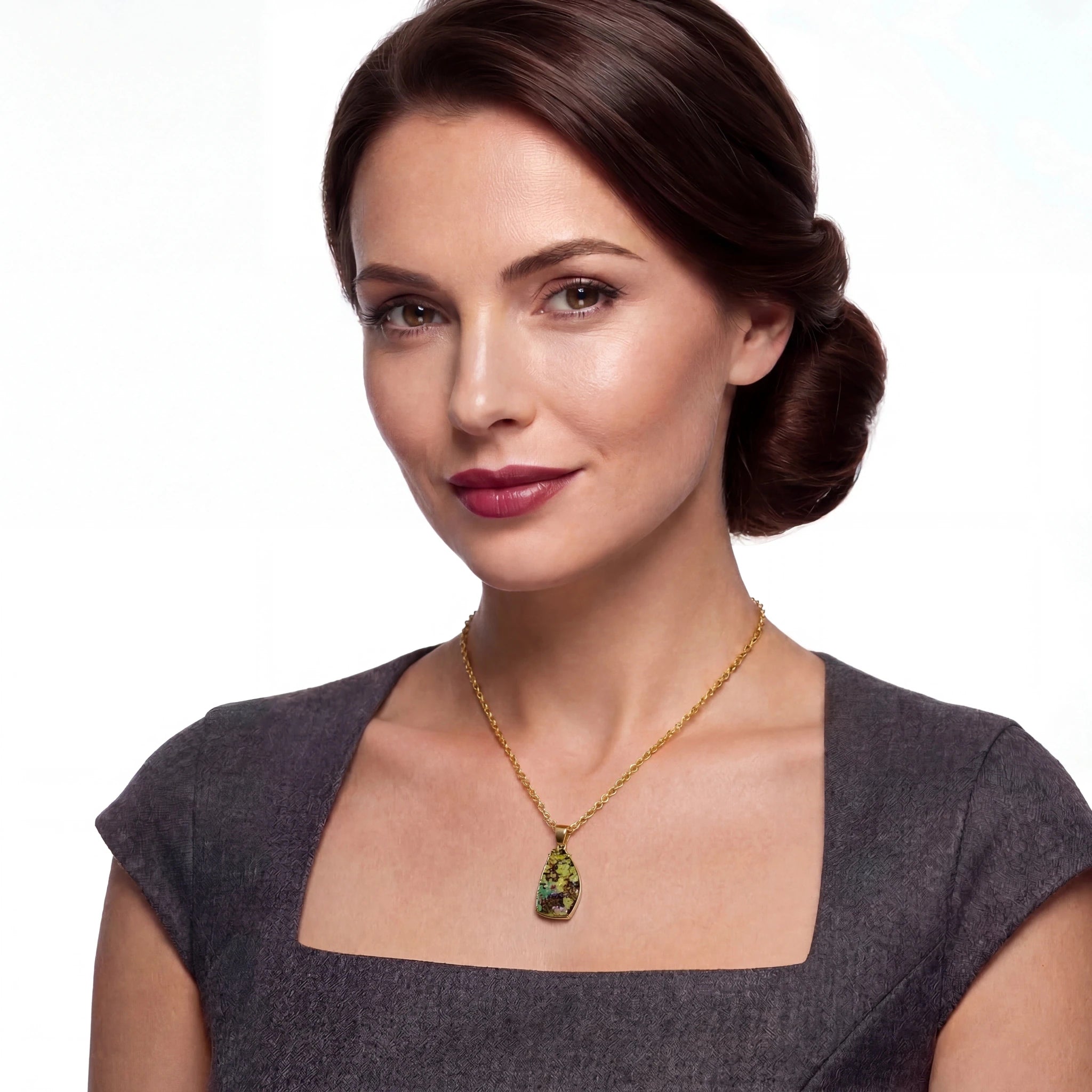 Woman wearing a gold necklace with a green opal pendant on a white background