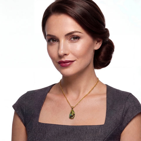 Woman wearing a gold necklace with a green opal pendant on a white background