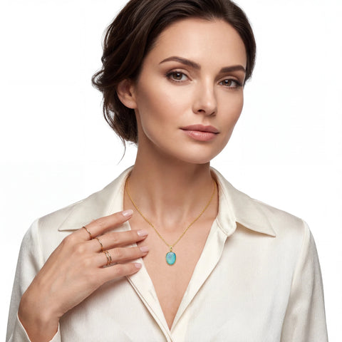 Woman wearing a gold necklace with a turquoise pendant on a white background