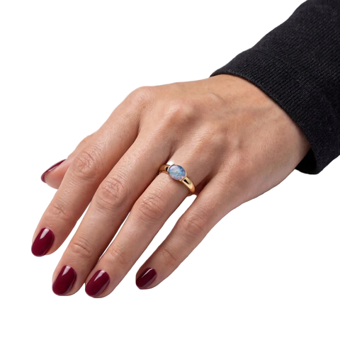 Woman wearing a gold ring with a blue opal gemstone