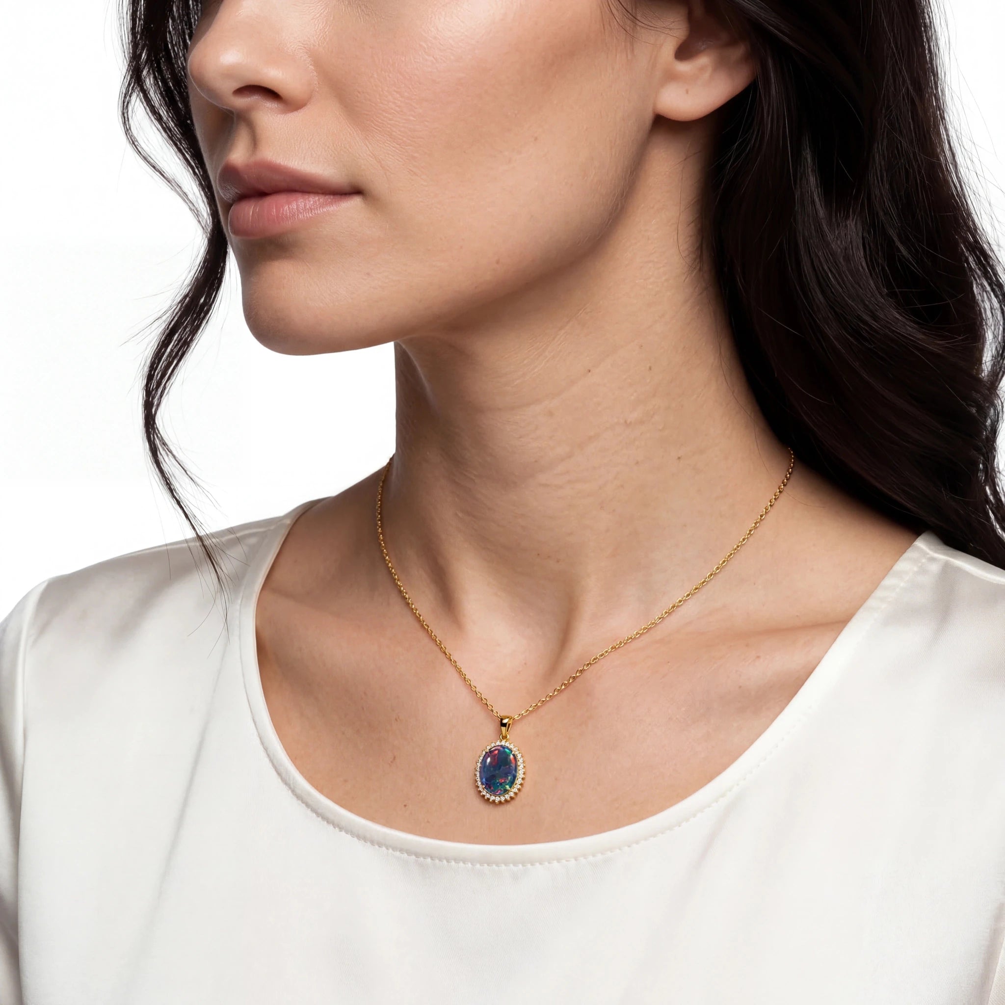 Woman wearing a gold necklace with a blue opal pendant on a white background