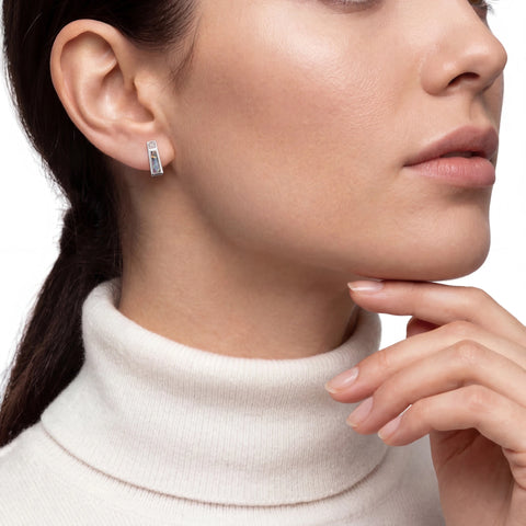Close-up of a woman wearing a silver opal earring with a white turtleneck sweater.
