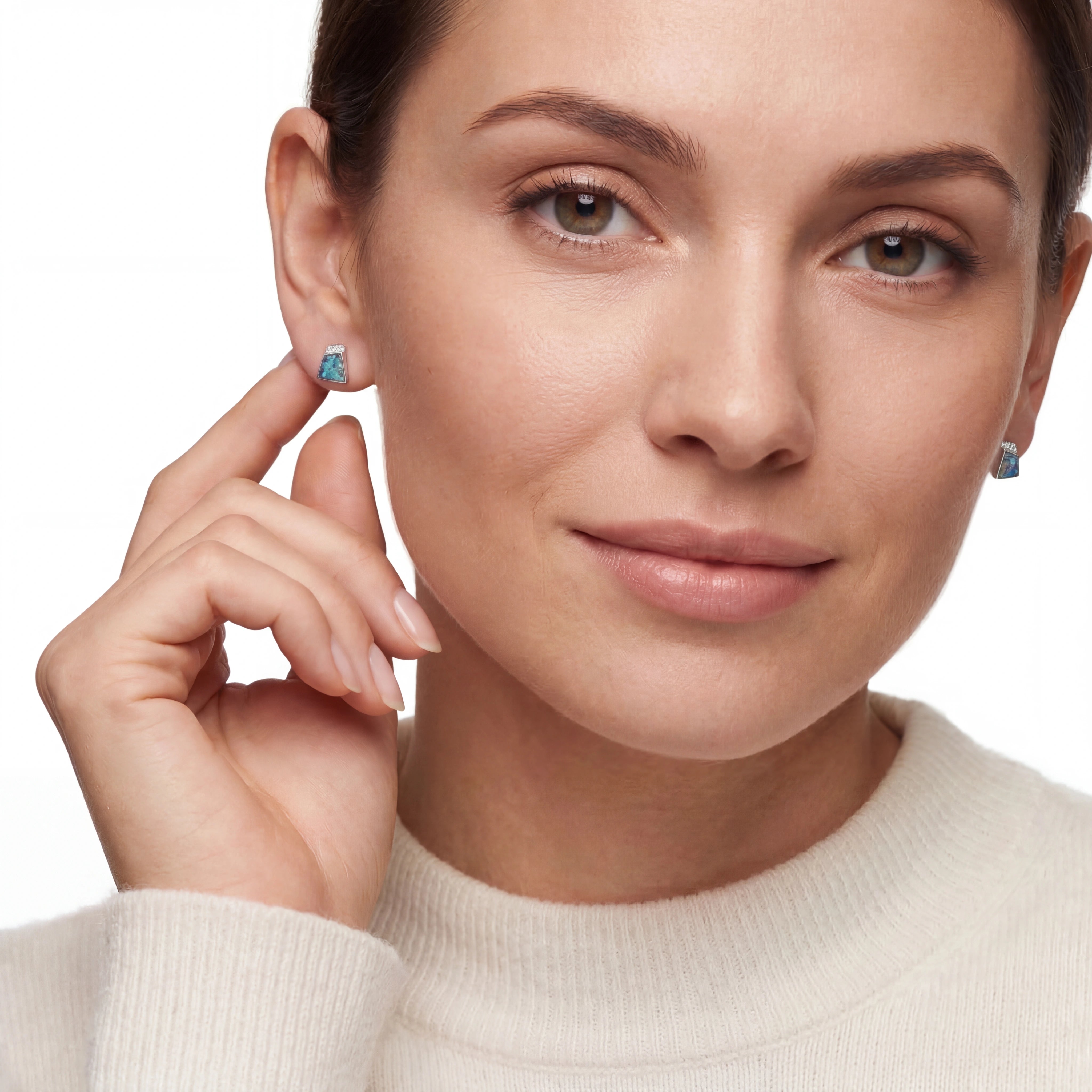 Close-up of a woman wearing opal earrings with a plain background