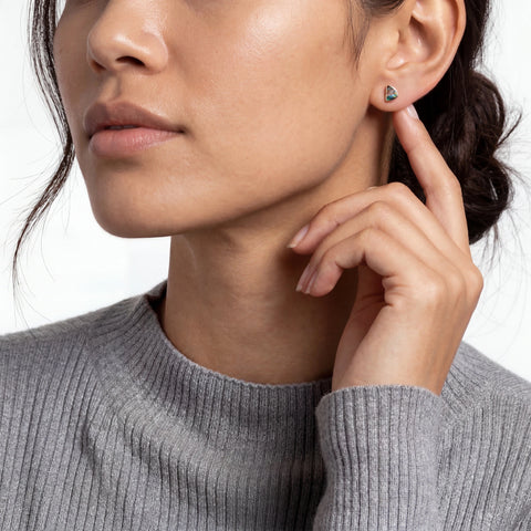 Close-up of a woman wearing a green heart-shaped earring.