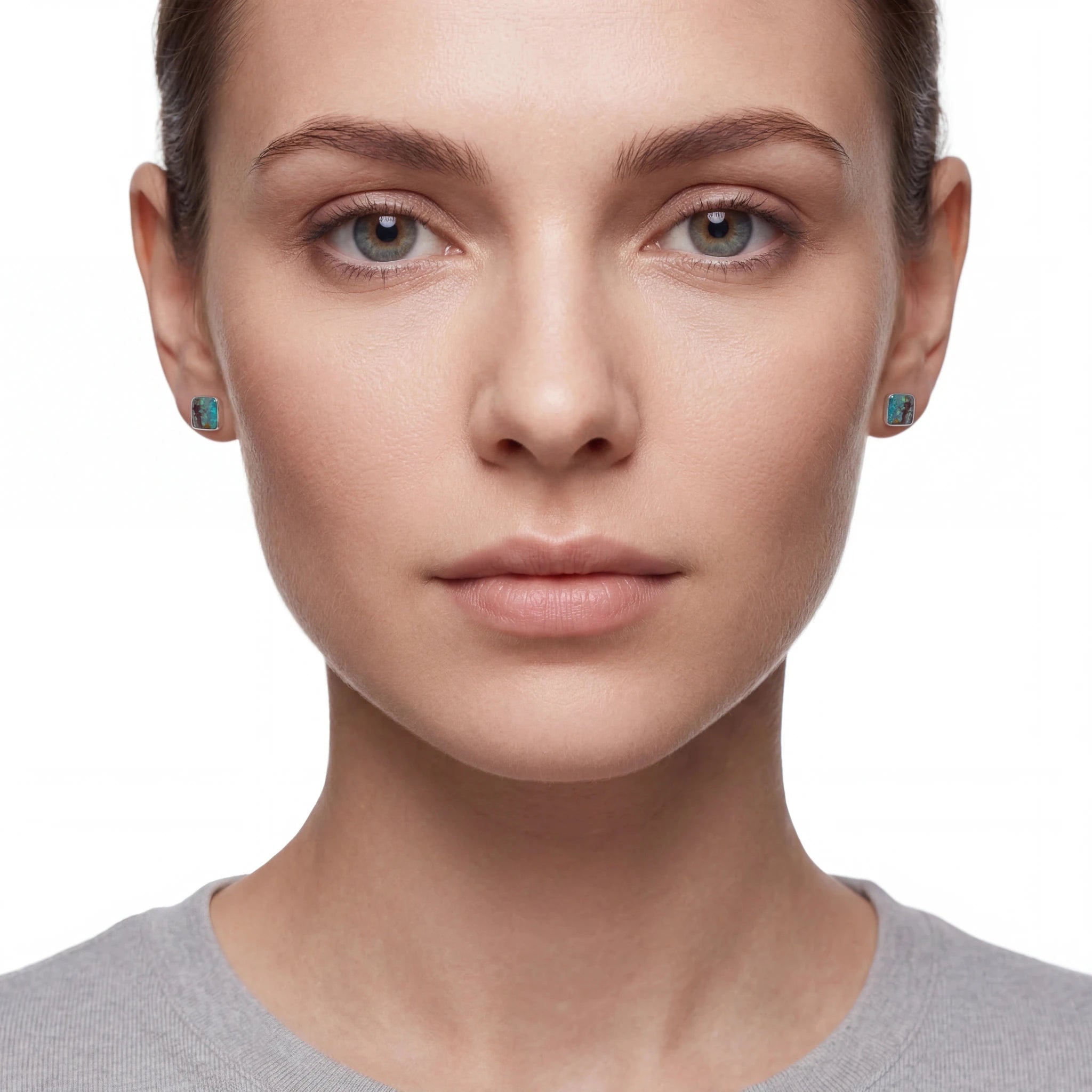 Close-up of a woman wearing turquoise earrings on a white background