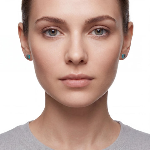 Close-up of a woman wearing turquoise earrings on a white background