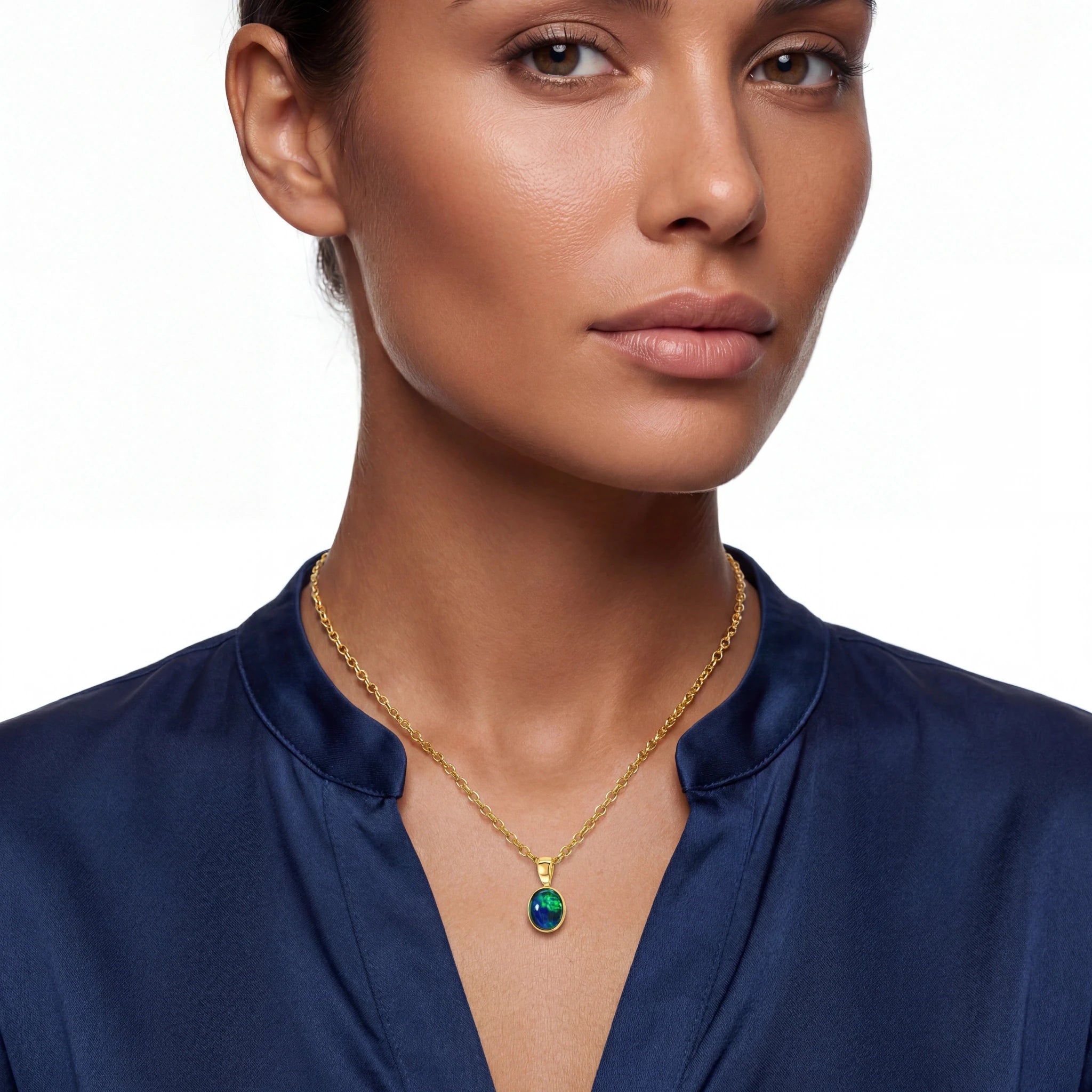 Woman wearing a gold necklace with a green gemstone on a white background