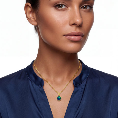 Woman wearing a gold necklace with a green gemstone on a white background