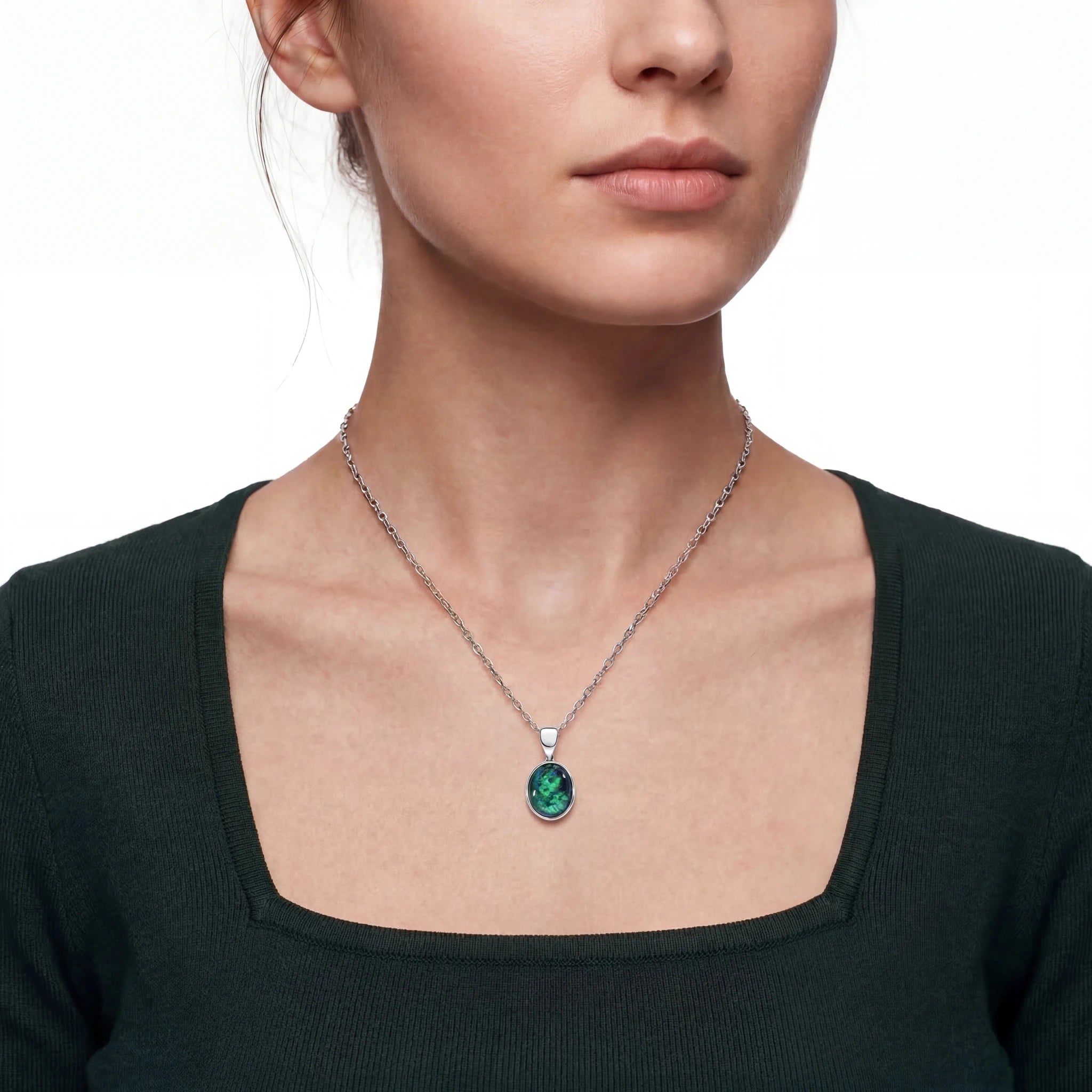Close-up of a woman wearing a necklace with a green gemstone on a white background