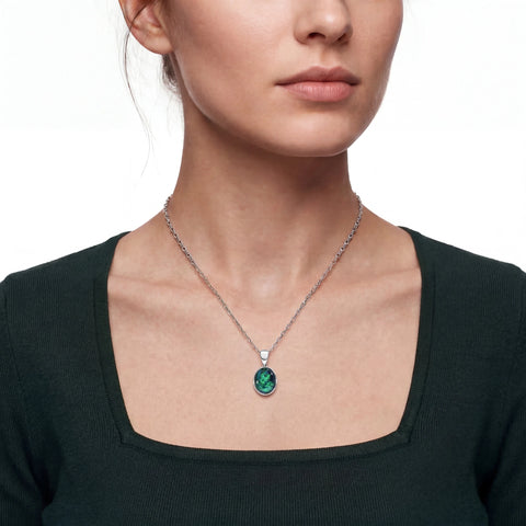 Close-up of a woman wearing a necklace with a green gemstone on a white background