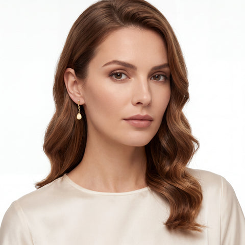 Woman wearing gold earrings with a plain background
