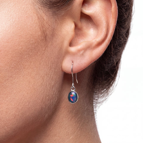 Close-up of an ear wearing a blue gemstone earring on a white background