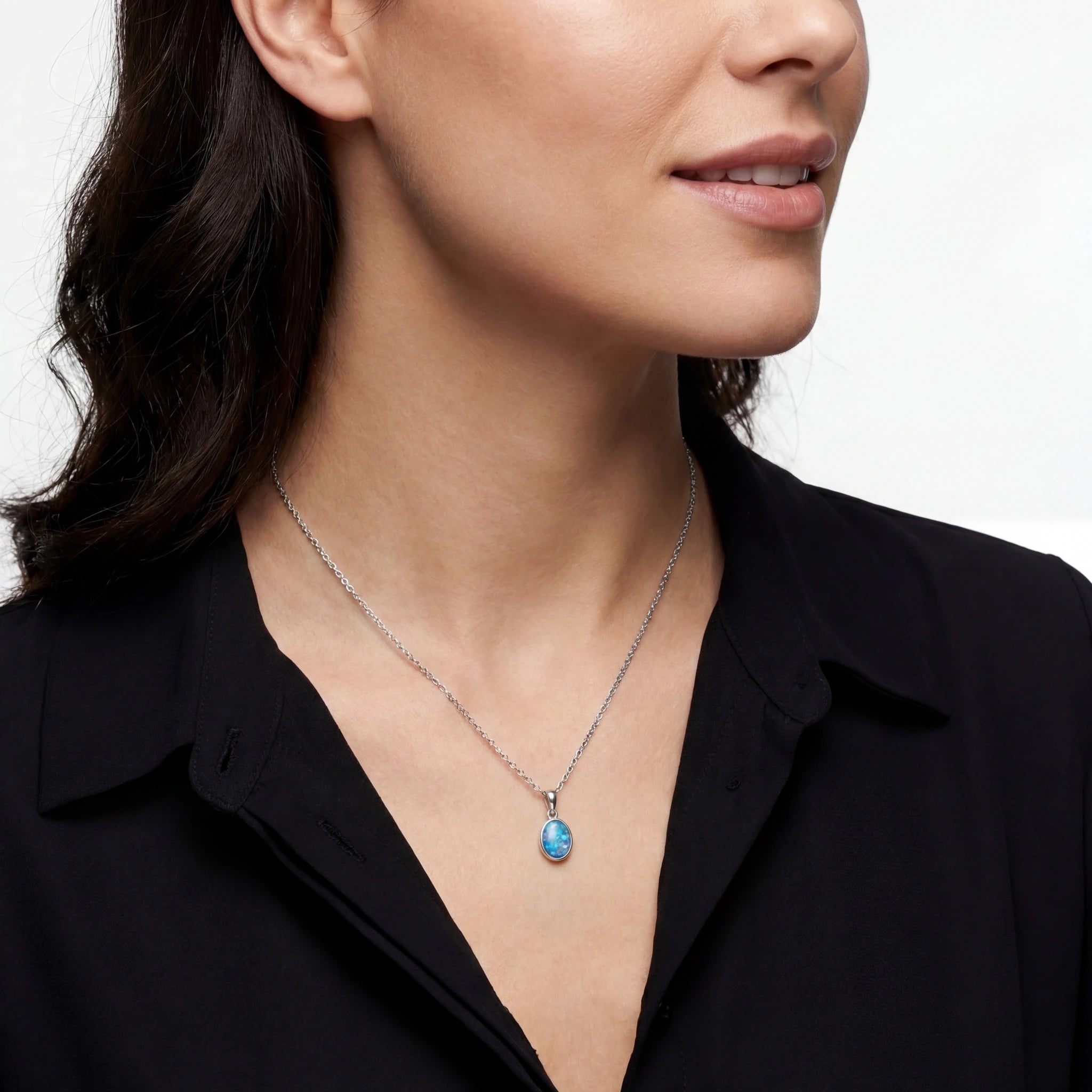 Woman wearing a necklace with a blue pendant against a neutral background