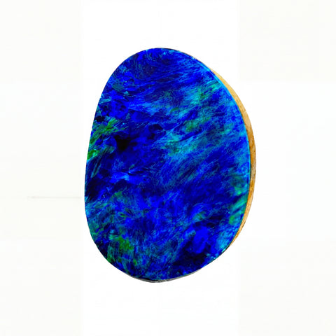 A polished, irregularly shaped cabochon gemstone featuring vibrant blue and green opal-like marbling, mounted on a light wood backing, shown against a plain white background.