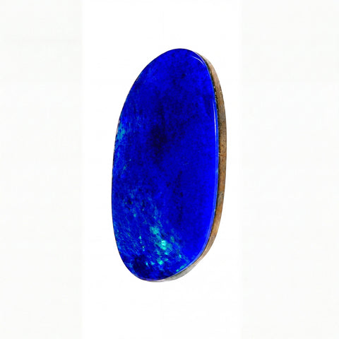 A polished oval опал gemstone in vibrant royal blue with natural tonal variations and a polished brown backing, shown on a clean white background.
