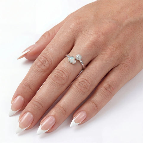 Hand wearing a silver ring with a heart-shaped gemstone on a white background