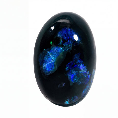 A polished oval opal gemstone featuring a deep black base with vibrant blue and green iridescent opal patterns, set against a plain white background.